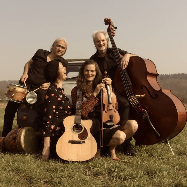 Coindra zu viert mit Instrumenten auf einem Feld